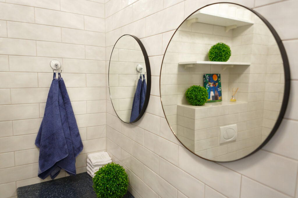Dwa okrągłe lustra zamocowane na ścianach łazienki za pomocą silikonu uszczelniającego